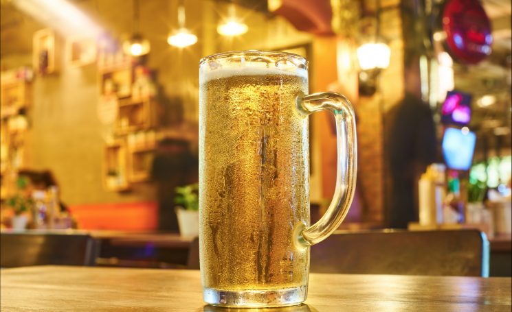 Tall glass of beer on bar in pub